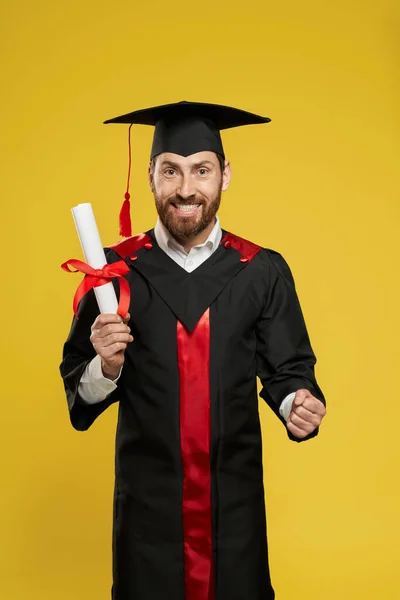 Мальчик с бородой стоит с дипломом, смотрит в камеру. — стоковое фото