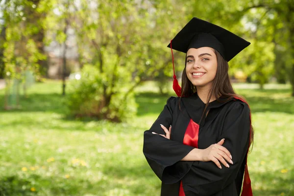 Menina vestindo argamassa e vestido de graduação sorrindo. — Fotografia de Stock