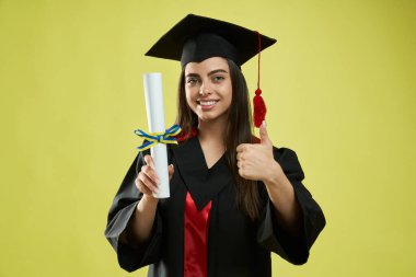 Girl in mortarboard and graduate gown holding diploma.