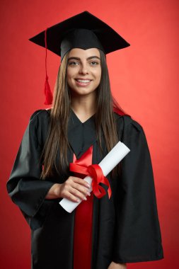 Elinde diplomayla kameraya bakan mutlu genç bir kadın..