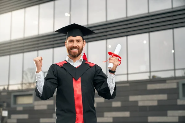 Mannelijke student in het bezit van een diploma, glimlachen, tonen hoera. — Stockfoto