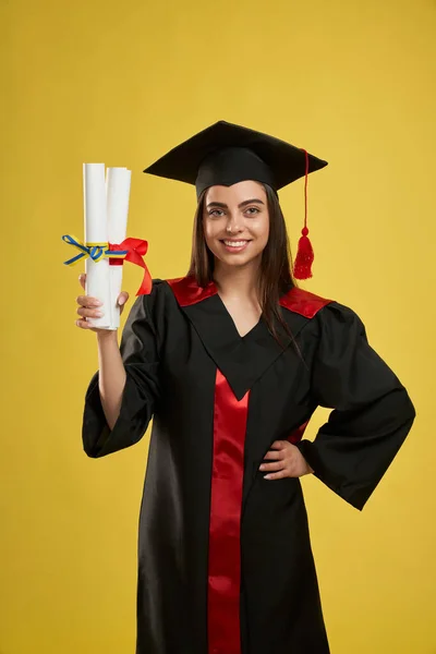 Mooie vrouwelijke afgestudeerde staande, met twee diploma 's. — Stockfoto