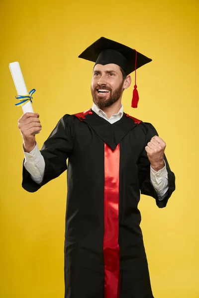 Absolvent s vousy držící diplom, ukazující hurá. — Stock fotografie