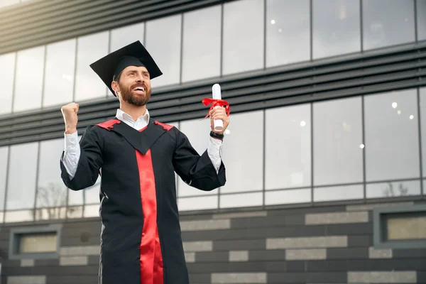 Student wearing mortarboard and graduate gown graduating from college. — Stockfoto