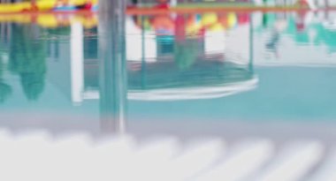 Water surface in swimming pool with reflection of sunbeds