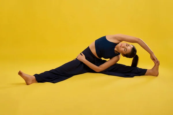 Femme mince pratiquant asana de yoga avec étirement en studio. — Photo