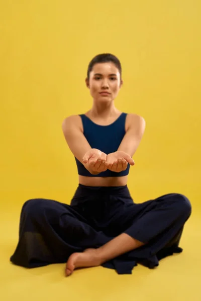 Жінка сидить у легкій позі йоги, розтягуючи руки вперед в приміщенні . — стокове фото