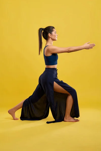 Pretty woman keeping arms stretched, while staying in yoga pose. — Stok Foto