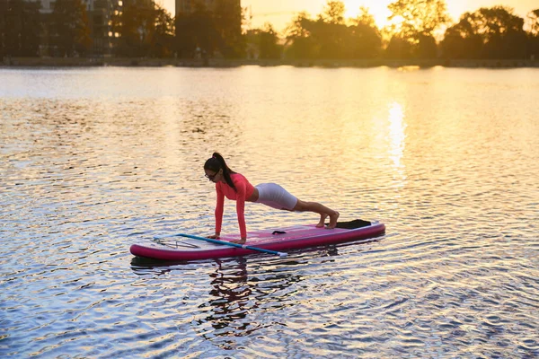 Sporty woman doing plank exercises on paddle board — Photo