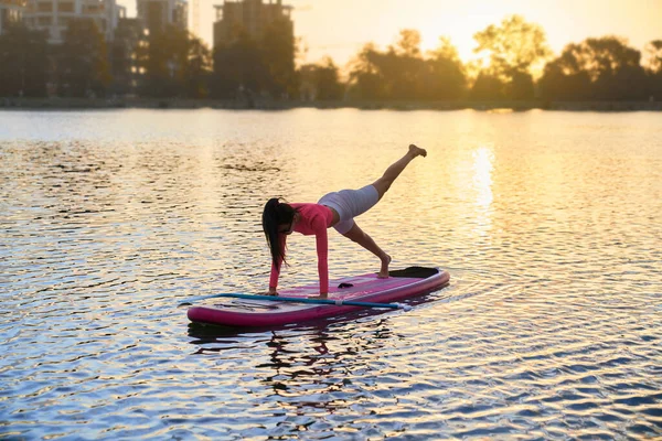 Frau balanciert auf Surfbrett bei Yoga-Übungen — Stockfoto