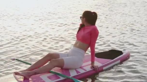 Relaxed woman lying on sup board on city lake — 图库视频影像