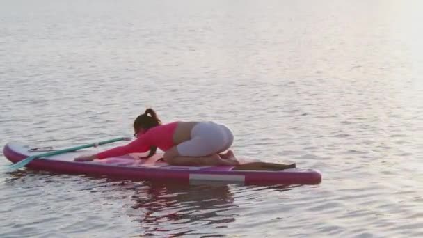 Caucasian woman doing stretching exercises on sup board — стоковое видео