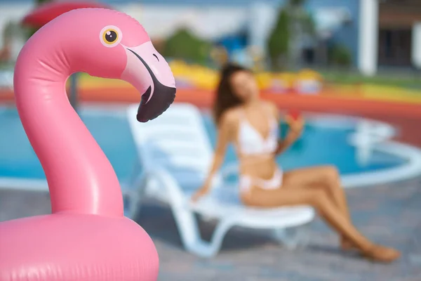 Närbild av rosa flamingo luftmadrass med suddig kvinna på bakgrunden. — Stockfoto