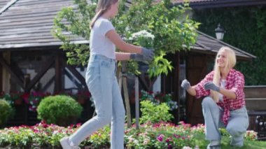 Güzel bir anne ve kızı açık havada çiçek ekiyor..