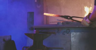 Demirci kırmızı sopası elinde maşayla.