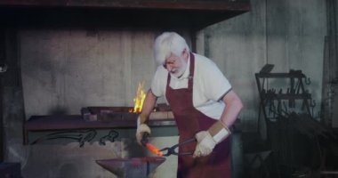 Demirci, elinde maşayla demir işçiliği yapıyor..