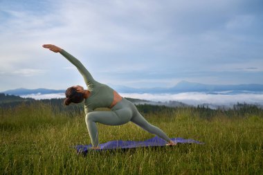 Esnek genç bir kadın dağların arasında eğitim görüyor.