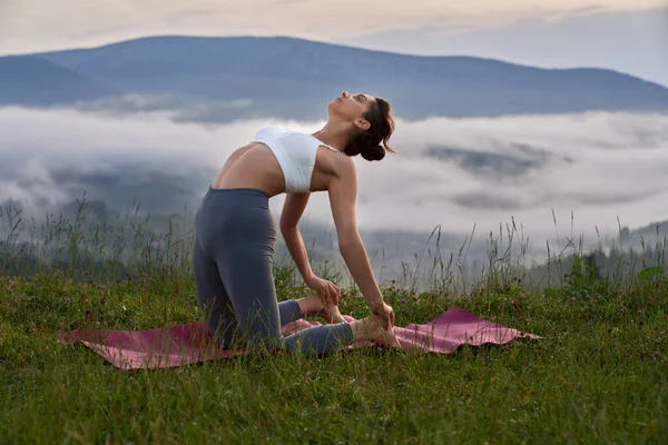Donna atletica stretching corpo su stuoia di yoga all'aperto — Foto Stock