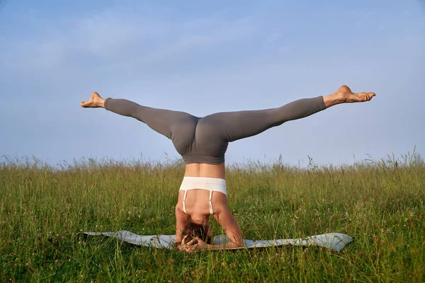 Donna in forma allungando le gambe mentre in piedi sulla testa all'aperto — Foto Stock