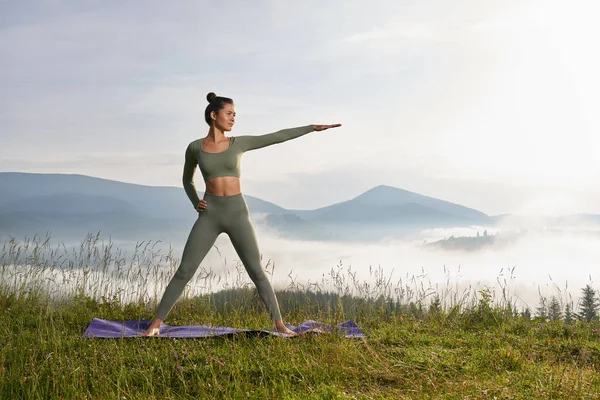 Adatta giovane donna che pratica yoga tra la natura verde — Foto Stock