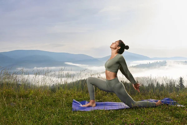 Donna sportiva stretching corpo su stuoia di yoga all'aperto — Foto Stock