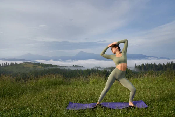 Donna che fa esercizio mattutino su tappetino yoga all'aperto — Foto Stock