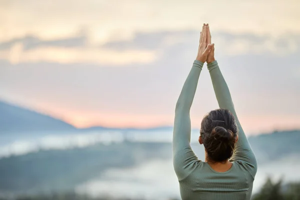 Donna che pratica yoga facendo posa guerriero di fronte a montagne nebbiose al mattino. — Foto Stock