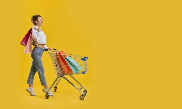 Girl walking on toes, driving shopping cart.