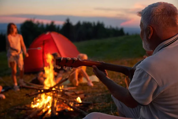 Alter Mann spielt Gitarre im Lager. — Stockfoto