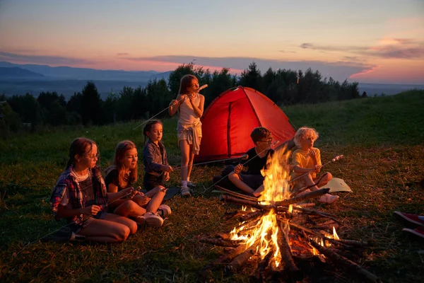 Gruppe von Kindern beim Essen auf dem Campingplatz in den Hügeln. — Stockfoto