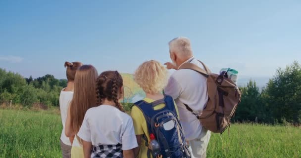 一群观光客站在一起 看地图 老男人和背包说话 显示地平线 孩子们在听 旅行及远足的概念 — 图库视频影像