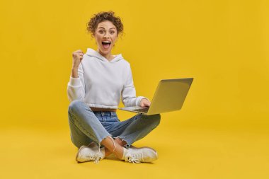 İçeride sınavı geçtiği için sevinen heyecanlı kız öğrenci. Mutlu kadın serbest çalışanın başarılı bir başlangıçtan hoşlandığına dair ön görüş, sarı arka planda izole edilmiş, yumrukla el kaldırma. Duygu kavramı.