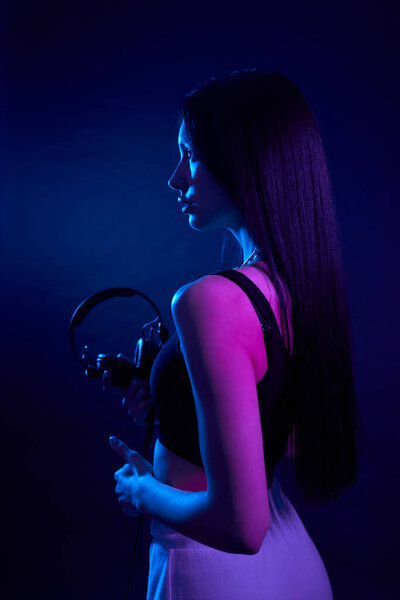 Graceful Long Haired Girl Holding Headphones Standing Straight Dark Studio Royalty Free Stock Images