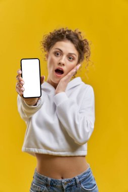 Kaygılı, bulanık bir kadının kapalı devre telefon ekranını açtığını gösteriyor. Akıllı telefonun beyaz ekranlı yakın görüntüsü, heyecanlı bir kızın elinde, turuncu stüdyo arka planında izole edilmiş. Aygıt kavramı.