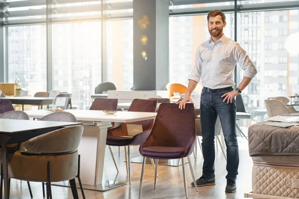 Exitoso Propietario Tienda Muebles Elegante Informal Apoyado Silla Mientras Posando — Foto de Stock