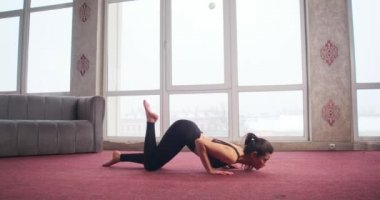 Side view of sporty, slim girl with ponytail standing on knees, bending, stretching, lying down. Beautiful, brunette woman exercising, practicing. Concept of new age and yoga.