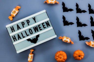 Cadılar bayramı arkaplanı. Koyu mavi ahşap bir masada balkabakları ve yarasalar. en üstteki görünüm.