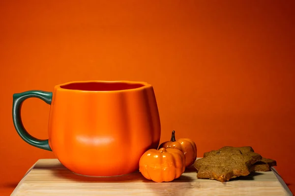 autumn pumpkin and cup of hot drink and pumpkins on a brown wooden background. halloween concept.