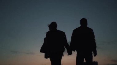 Arkaya bakan karanlık siluetler. Uzaklaşıp el ele tutuşan çift..