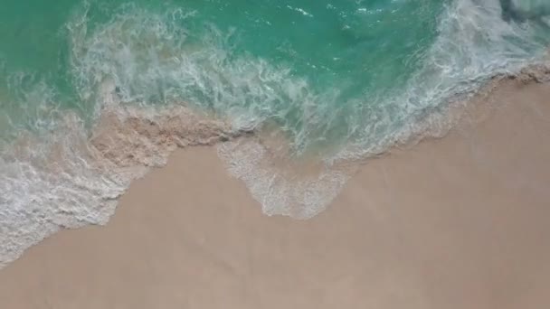Vue de dessus au ralenti des vagues mousseuses sur une plage de sable blanc