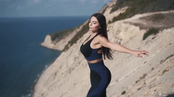 Schöne brünette Europäerin in Sportbekleidung hebt die Arme zur Seite — Stockvideo