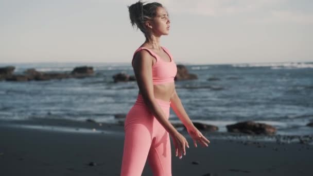 Side view of beautiful young woman doing squats at the seashore. — Stock Video