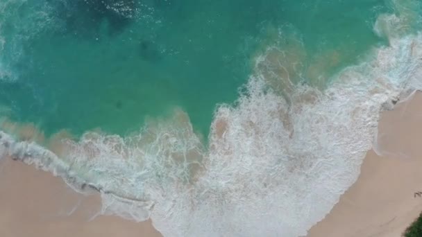 Vista superior en cámara lenta de las olas salpicadas de espuma de mar en una playa de arena blanca — Vídeo de stock