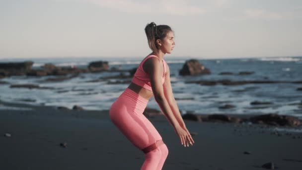 Vista lateral de la mujer joven haciendo sentadillas y piernas columpios laterales. — Vídeo de stock