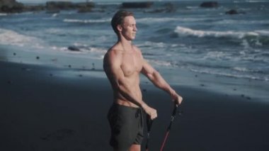 Mükemmel vücut sporcusunun yan görüntüsünü kapat. Kollarını elastik bantla kaldır..