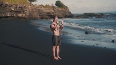 Mükemmel vücut sporcusu, kollarını elastik bantla eğitir..