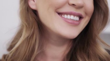 İffetli, esmer, büyük bir gülümsemesi olan sarışın kız.