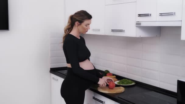 Frau hält ihren Schwangerschaftsplan ein und macht einen Gemüsesalat — Stockvideo