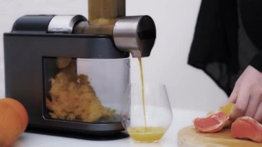 Taze narenciye suyu sıkan bir kadının yakın plan çekimi. Meyve sıkacağı makinesiyle greyfurt ve portakal vitamini yapmak. Sağlıklı besleniyorum.