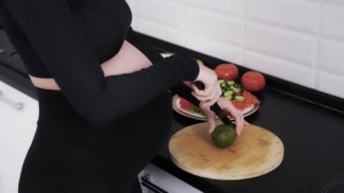 Hamile bir kadının öğle yemeği için sağlıklı yemek pişirdiği bir yüz resmi yok. Müstakbel anne sebze salatası için avokado kesiyor. Organik ve sağlıklı yiyecekler yiyorlar. Bir bebek için vitaminler